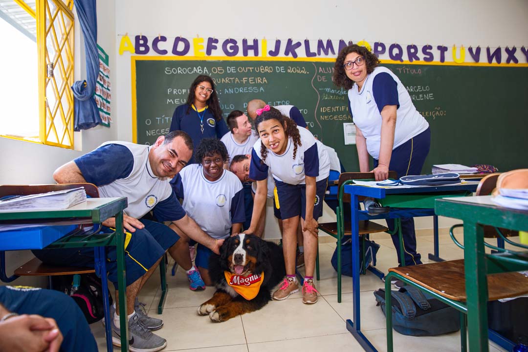 Alunos acariciando o cão Magnus, mascote do Instituto Adimax, dentro de uma sala de aula em uma visita à crianças de um Centro de Educação Especial.