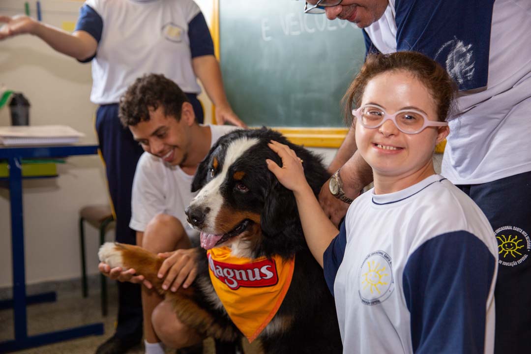 Alunos acariciando o cão Magnus, mascote do Instituto Adimax, em uma visita à crianças em um Centro de Educação Especial.