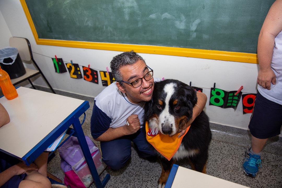Na imagem aluno abraça o cão Magnus  dentro da sala de aula